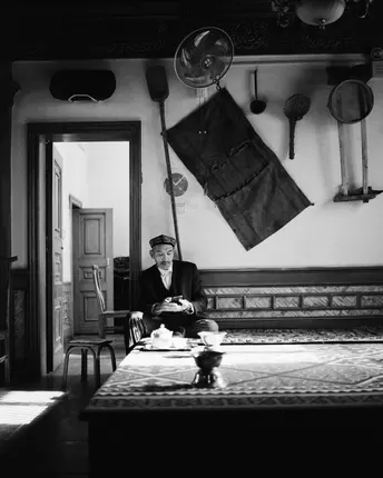 一张黑白照片 一位穿着西装的男子坐在餐桌旁