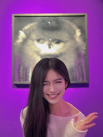 一位年轻女子在紫色的猫画前摆姿势拍照