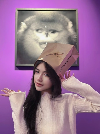 一位年轻女子举着一个纸袋在头上 里面有一只猫在一个盒子中。