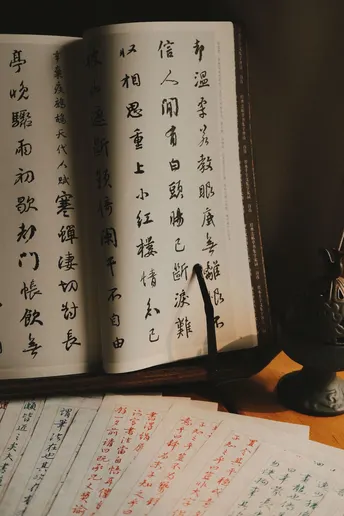 桌子上放着一本打开的书 上面有中文纸张。