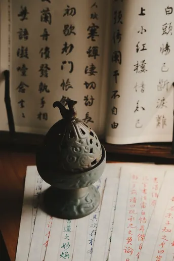 一个小茶壶坐在一个有中文的书旁边 书桌旁边