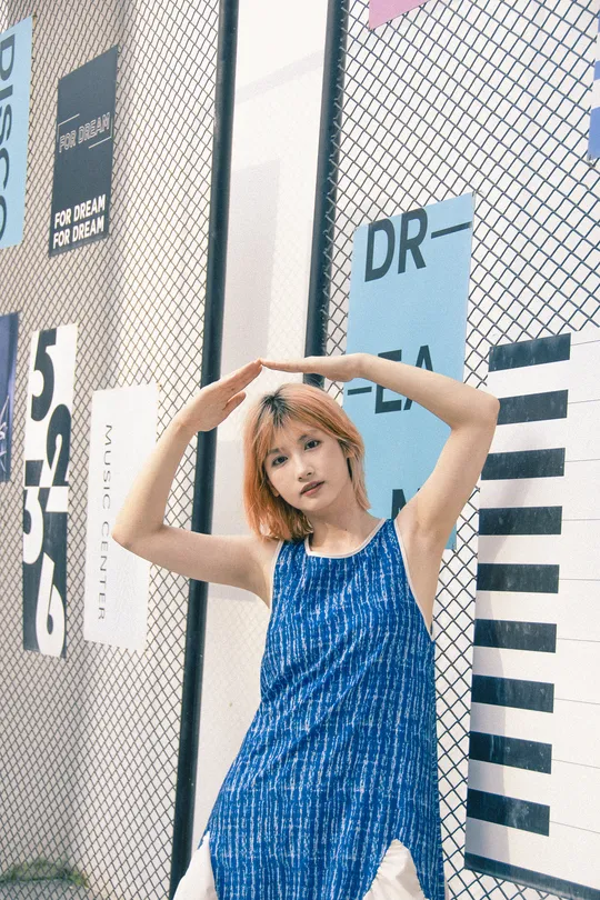 一位穿着蓝色连衣裙的年轻女子站在围栏前 双手背后