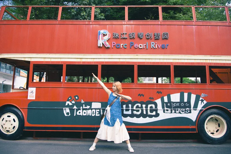 一位站在街上的红色双层公交车前的女性