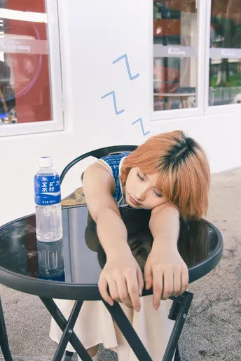 一个年轻女子坐在桌子旁 靠在一把黑色椅子上 头靠在椅背上。