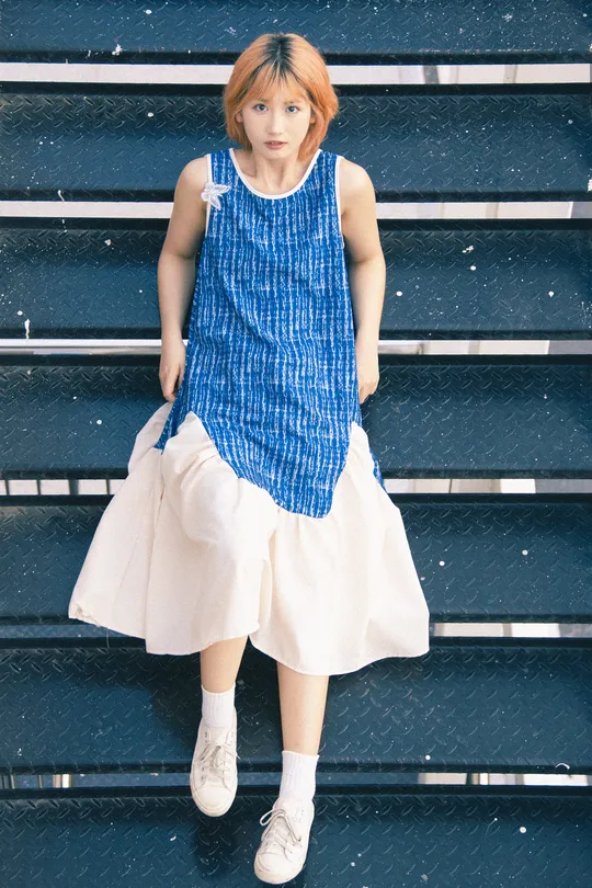 一位穿着蓝色连衣裙和白色裙子的年轻女子坐在楼梯上