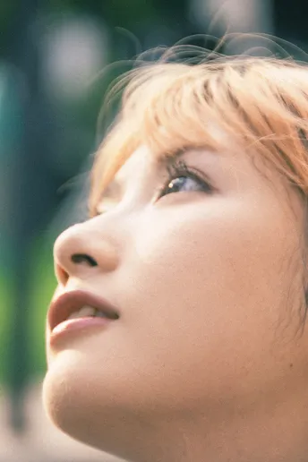 一位金发年轻女子抬头仰望天空 脸上带着严肃的表情 这是一张特写肖像。