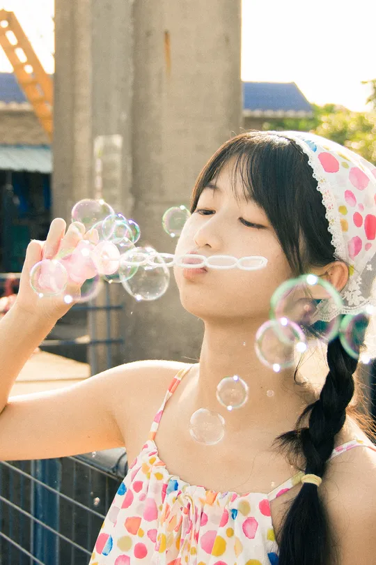 一位年轻女子在晴朗的阳光下在户外吹泡泡。