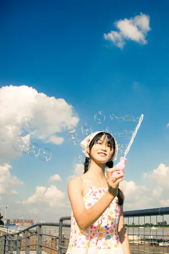 一个小女孩穿着裙子在天空中吹泡泡