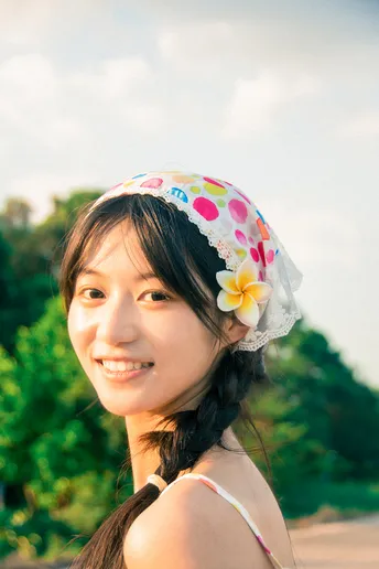 一位戴着一顶有花在头上的帽子 站在海滩上的年轻女子