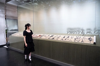 一位穿着黑色连衣裙的女人站在一面墙前