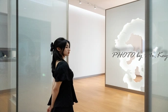 站在白色墙壁前 凝视着玻璃柜的年轻女子