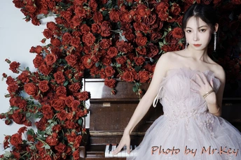 一个穿着晚礼服的女人在钢琴和红玫瑰前摆姿势