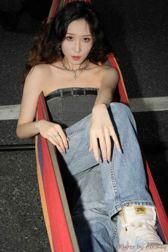 一个年轻女子坐在吊床上 穿着破洞牛仔裤。