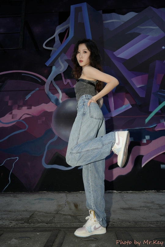 一位年轻女子交叉双腿站在涂鸦墙前