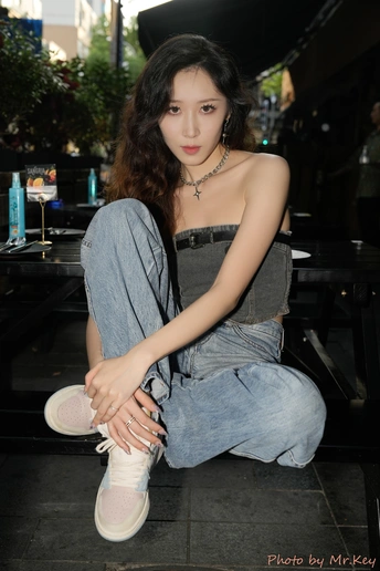 一个穿着牛仔裤和白色鞋子的年轻女子坐在地板上