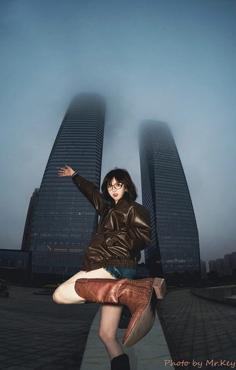 一位年轻女子交叉双腿站在城市的高楼前