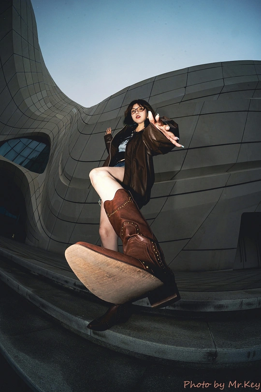 一位女性站在滑板上 双腿交叉在建筑物前拍照。