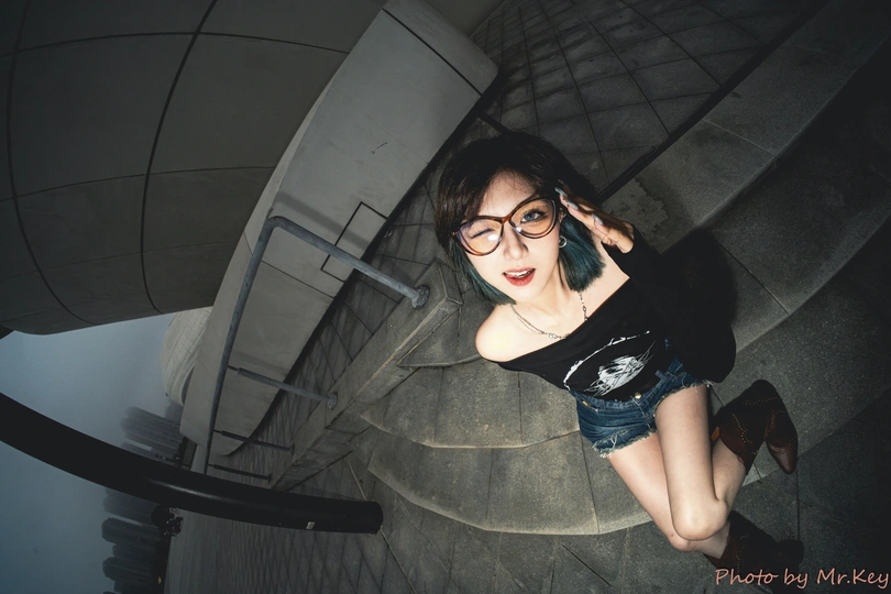 一个戴眼镜的年轻女子坐在螺旋楼梯上打电话