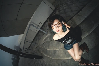 一个戴眼镜的年轻女子坐在螺旋楼梯上打电话