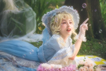 一位穿着蓝白色裙子的女士坐在户外吹泡泡。