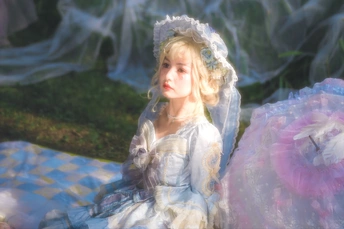 一个穿着白裙子的年轻女孩坐在草地上