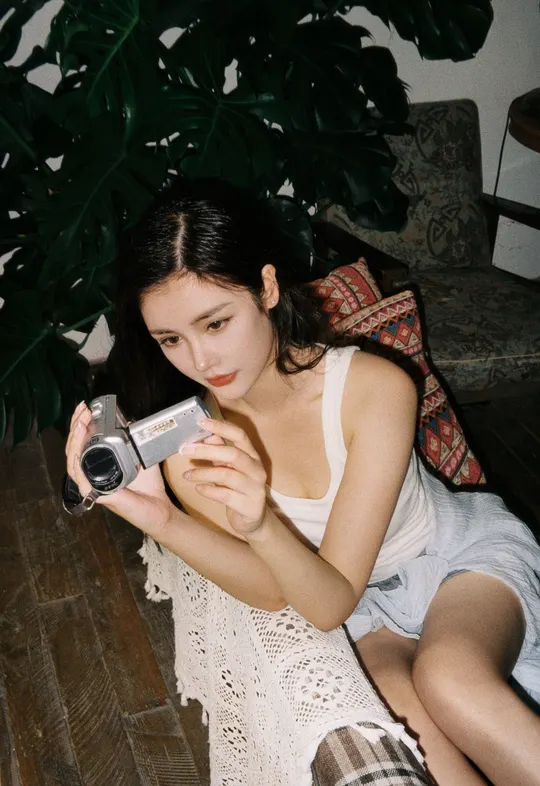 一位年轻女子抱着相机坐在地板上