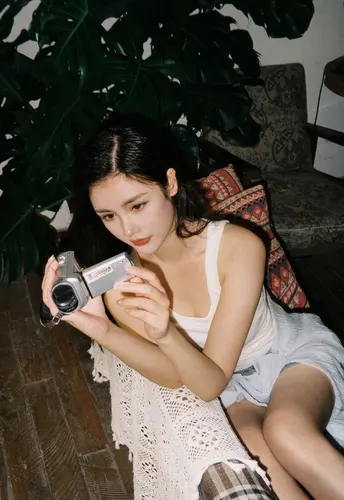 一位年轻女子抱着相机坐在地板上