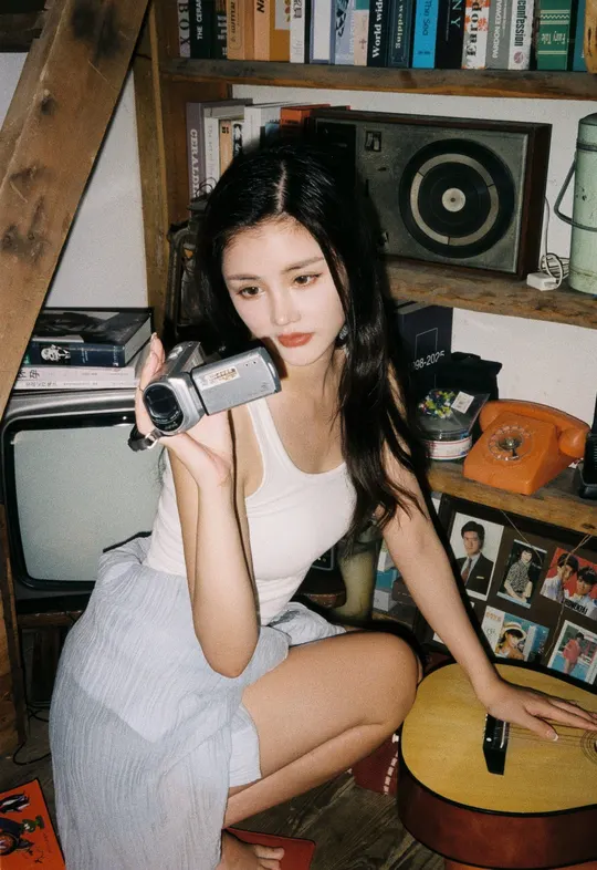 一位年轻女子坐在凌乱的房间里 手里拿着相机