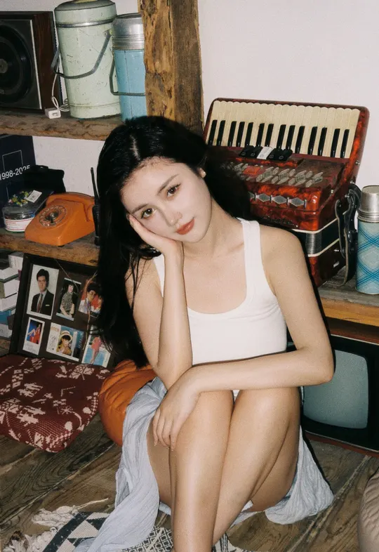 一个年轻女子坐在凌乱的房间里 床上有床单。