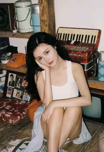 一个年轻女子坐在凌乱的房间里 床上有床单。