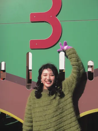 站在绿色标志前的一个女人 上面有大的字母