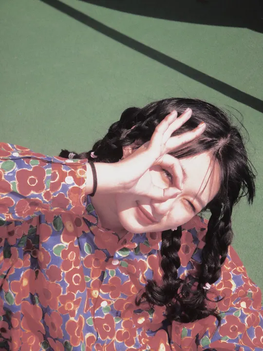 一个穿着连衣裙的年轻女子躺在网球场地板上 双手捂住脸