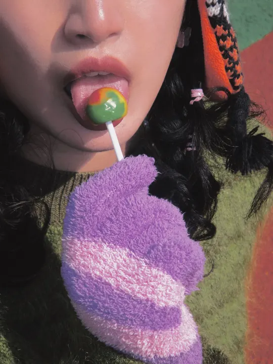 一位年轻女子用吸管在她嘴唇前面拿着棒棒糖