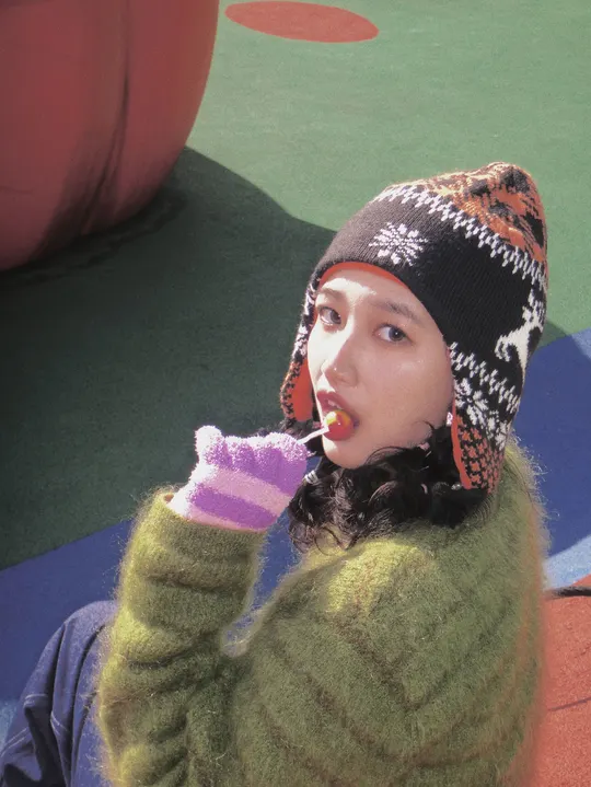 一位戴绿帽子的小女孩正在用牙刷刷她的嘴。