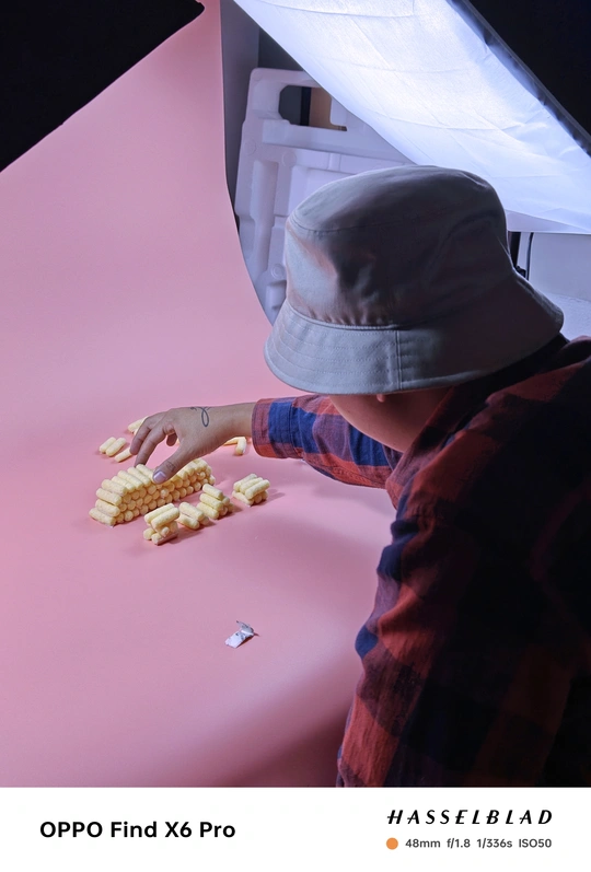 一个年轻人正在从一张粉红色桌子那里拿一些玉米。