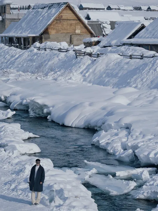 一个站在雪和冰旁边的小溪流旁的人