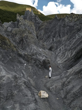 一个人站在岩石上 背景是山脉。