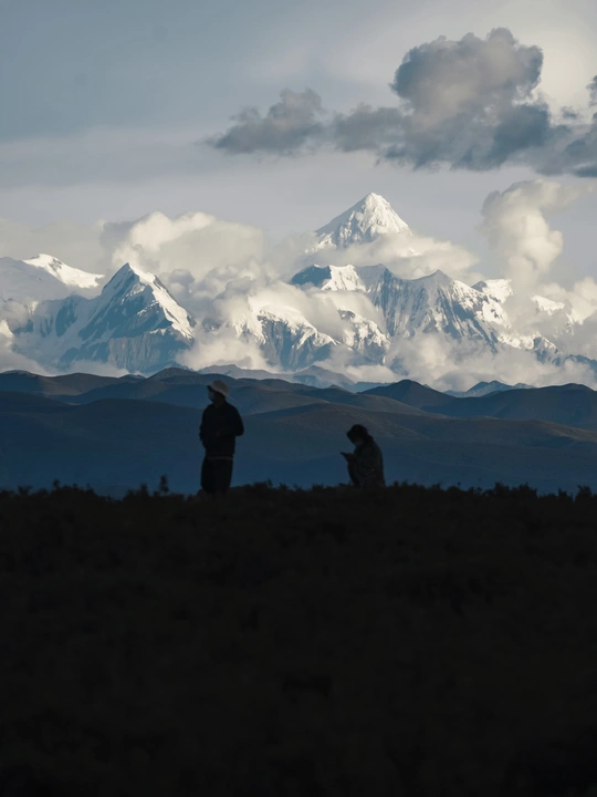 人们坐在山顶上 眺望雪山的轮廓