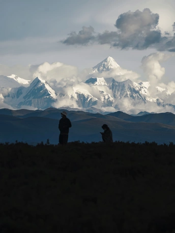 人们坐在山顶上 眺望雪山的轮廓