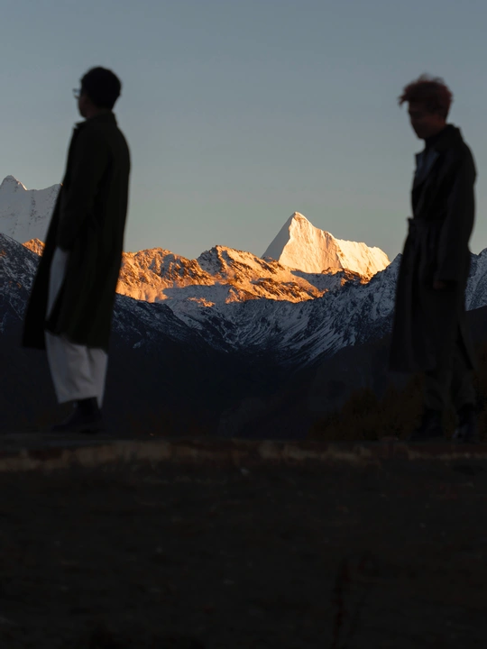 夕阳下 几名男子站在山脉前 其中一人眺望着远方。