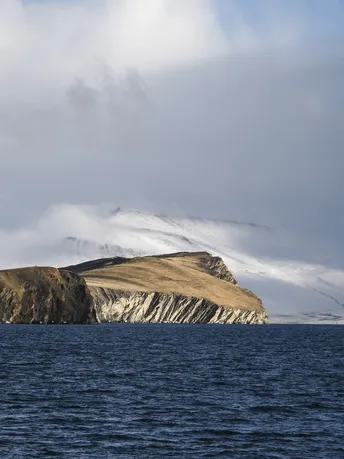 中间有一座岛屿 周围是水、山丘和云彩。