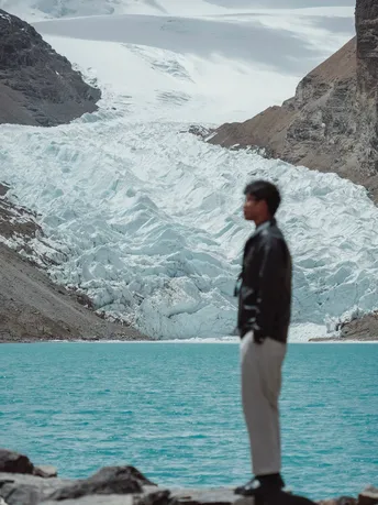 站在冰川前 凝视着蓝色水域的男子