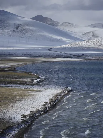 雪景 山丘 山脉和前景流动的水体 冬季