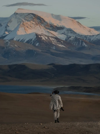 一位妇女穿过一片荒凉的景观 背景是山脉。