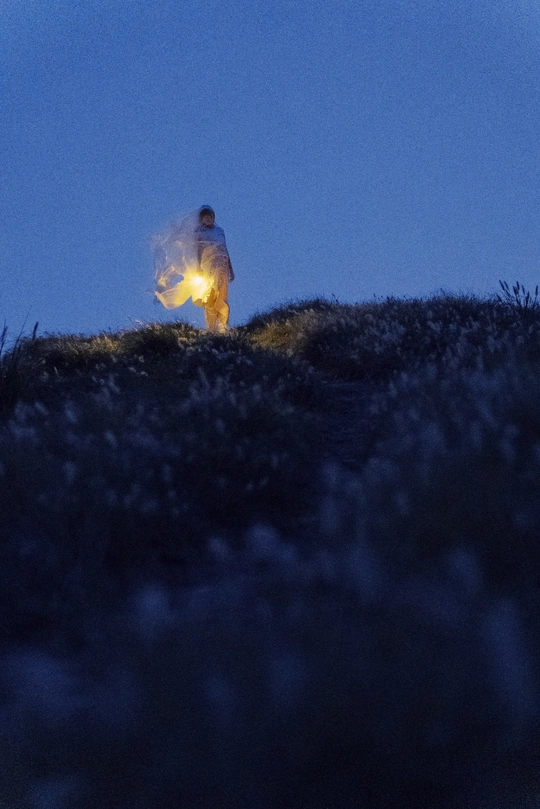 一个人站在山顶上 手里拿着一支点燃的蜡烛在灯笼里。