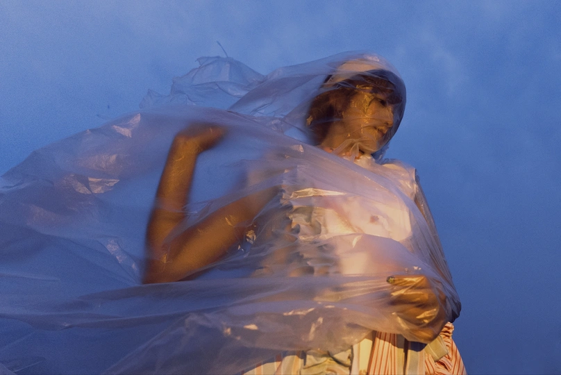 一个穿着由塑料布制成的裙子站在蓝色的天空中