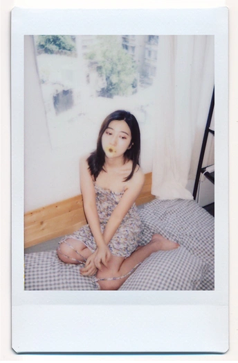 一个年轻女子坐在床上 嘴里含着苹果。