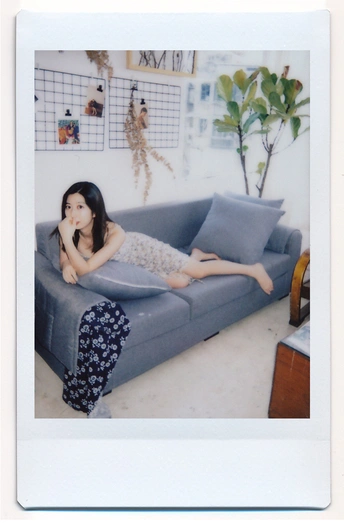 一位年轻女子躺在客厅里的蓝色沙发上的一幅画