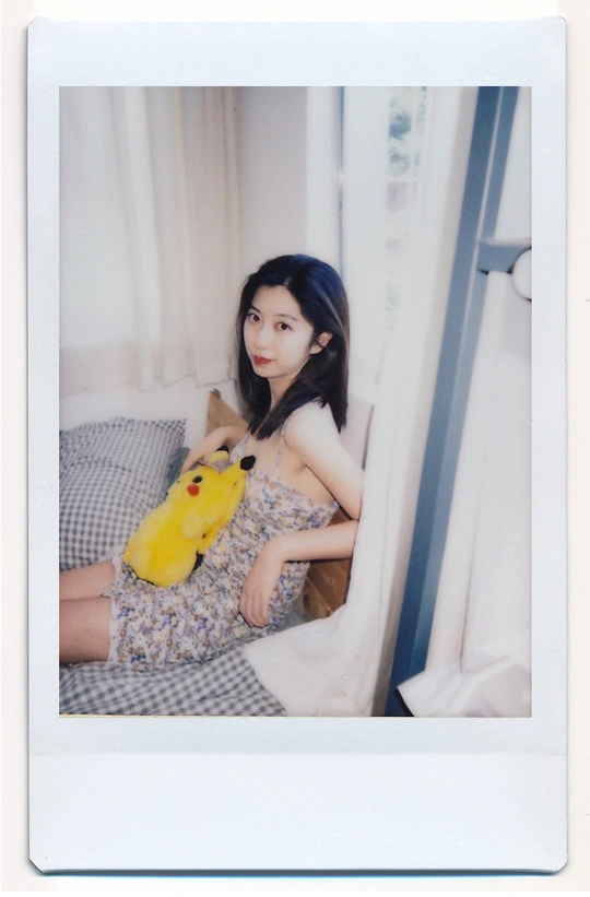 一张年轻女子抱着一只黄色毛绒玩具坐在床上的照片