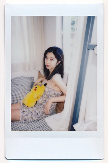 一张年轻女子抱着一只黄色毛绒玩具坐在床上的照片